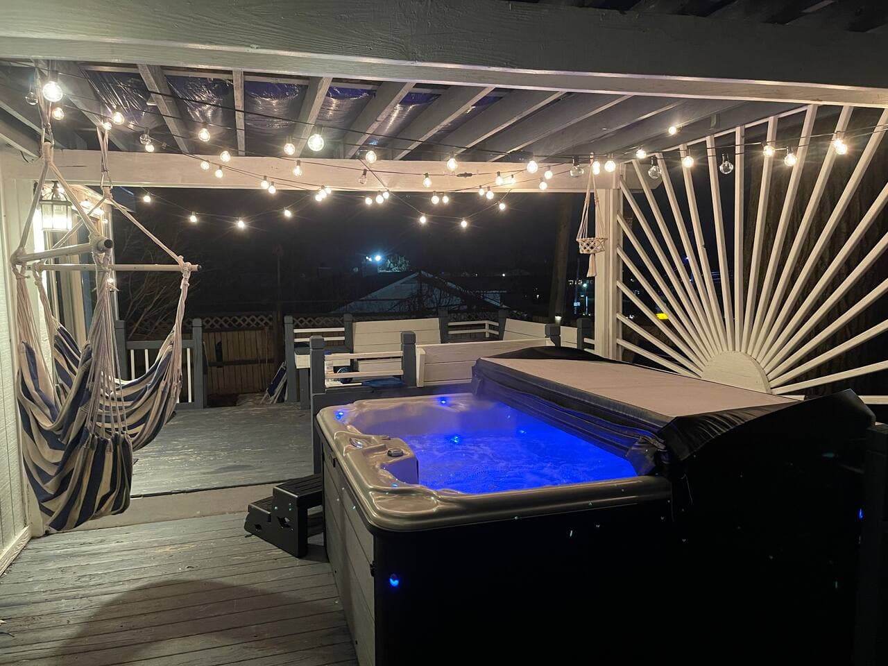 Hot tub glowing at night under string lights